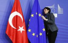 A staff adjusts European Union and Turkish (L) flags ahead of the arrival of Turkey's Prime Minister Tayyip Erdogan (not pictured) at the EU Commission headquarters in Brussels, January 21, 2014. PHOTO BY REUTERS/Francois Lenoir