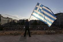 A man waves a Greek national flag while standing at the premises of the parliament building during a rally in front of the parliament building calling on the government to clinch a deal with its international creditors and secure Greece's future in the Eurozone, in Athens, Greece, June 22, 2015. PHOTO BY REUTERS/Yiannis Liakos/Intimenews