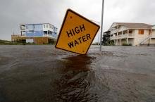 Flood waters lap at a high water warning sign that was partially pushed over by Hurricane Florence on Oak Island, North Carolina, U.S., September 15, 2018. PHOTO BY REUTERS/Jonathan Drake