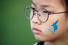 A blue silhouette of the Korean peninsula, which is used in the unification flag, is seen on a girl's face during a rally to wish a successful inter-Korean summit, in central Seoul, South Korea, April 21, 2018. PHOTO BY REUTERS/Kim Hong-Ji