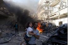 A man carries a girl as they rush away from a site hit by what activists said were airstrikes by forces loyal to Syria's President Bashar al-Assad in the Douma neighborhood of Damascus, Syria, August 24, 2015. PHOTO BY REUTERS/Bassam Khabieh
