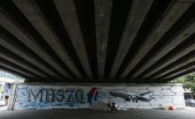 A man walks past graffiti of the missing Malaysia Airlines Flight MH370 in Kuala Lumpur