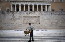 A member of the Greek Presidential guard walks next to a stray dog in front of the parliament building in Athens, Greece, August 22, 2015. PHOTO BY REUTERS/Stoyan Nenov