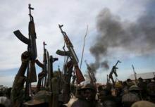 Rebel fighters hold up their rifles as they walk in front of a bushfire in a rebel-controlled territory in Upper Nile State, South Sudan, 2014. PHOTO BY REUTERS/Goran Tomasevic