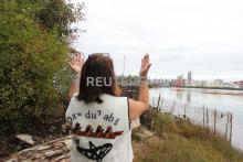 Duwamish Tribal Services Executive Director Jolene Haas holds up her hands, a traditional gesture of gratitude, on the banks of the Duwamish River in Seattle, USA. PHOTO BY Thomson Reuters Foundation/Gregory Scruggs