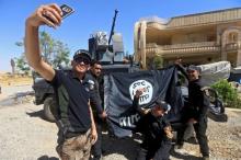 Members of the Iraqi Army are photographed with an Islamic State flag, claimed after fighting with Islamic State militants in western Mosul, Iraq, June 26, 2017. PHOTO BY REUTERS/Alaa Al-Marjani