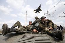 A fighter jet flies above as Ukrainian soldiers sit on an armoured personnel carrier in Kramatorsk, in eastern Ukraine, April 16, 2014. PHOTO BY REUTERS/Marko Djurica
