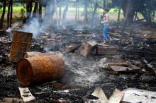 A journalist walks amongst the burnt-out remains of houses at Shwe Lay village, outside of Thandwe in Rakhine state, October 2, 2013. PHOTO BY REUTERS/Soe Zeya Tun