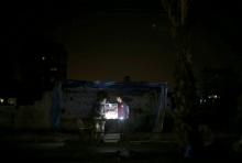 A Palestinian vendor uses battery-powered lights as he sells cigarettes during power cut at Shati refugee camp in Gaza City. PHOTO BY REUTERS/Mohammed Salem