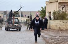 A man runs as a Free Syrian Army fighter stands on a back of a truck after what activists said were clashes between the Free Syrian Army and forces loyal to Syria's President Bashar al-Assad in Hama province