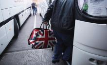 A man carrying a bag adorned with a British Union Jack flag steps into a bus departing from Sofia's central bus station to London via Austria, Germany and France, January 2, 2014. PHOTO BY REUTERS/Stoyan Nenov