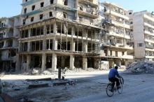 A man rides a bicycle near damaged buildings in the rebel held besieged al-Sukkari neighbourhood of Aleppo, Syria, October 19, 2016. PHOTO BY REUTERS/Abdalrhman Ismail