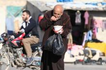 A man eats food that was distributed as aid in a rebel-held besieged area in Aleppo, Syria, November 6, 2016. PHOTO BY REUTERS/Abdalrhman Ismail
