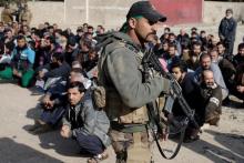 Men sit on the ground as an Iraqi Special forces intelligence team check their ID cards as they search for Islamic State fighters in Mosul, Iraq, November 27, 2016. PHOTO BY REUTERS/Goran Tomasevic