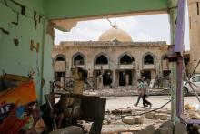 Iraqi men walk past a damaged building after the end of the battles between the Iraqi forces and Islamic State militants at their district in western Mosul, Iraq, April 30, 2017. PHOTO BY REUTERS/Muhammad Hamed