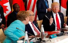 German Chancellor Angela Merkel (L) sits next to Tunisia's President Beji Caid Essebsi (C) and speaks to U.S. President Donald Trump (R) as they attend a G7 expanded session during the G7 Summit in Taormina, Sicily, Italy, May 27, 2017. PHOTO BY REUTERS/Philippe Wojazer
