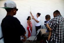 A Central American migrant, moving in a caravan through Mexico and traveling to request asylum in U.S, checks her health status as she arrives to Mexicali, Baja California state, Mexico, April 25, 2018. PHOTO BY REUTERS/Edgard Garrido