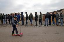 On the eve of International Migrants Day by United Nations, a Kurdish child from Iraq plays with a trotinette as migrants queue for food at a camp for migrants in Grande Synthe, France December 17, 2016. PHOTO BY REUTERS/Pascal Rossignol