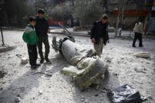 People inspect missile remains in the besieged town of Douma, in eastern Ghouta, in Damascus, Syria, February 23, 2018. PHOTO BY REUTERS/Bassam Khabieh