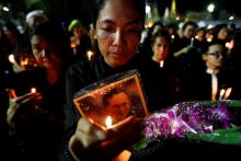 Mourners hold candles as they gather outside of the Grand Palace to sing for a recording of the royal anthem in honour of Thailand's late King Bhumibol Adulyadej in Bangkok, Thailand, October 22, 2016. PHOTO BY REUTERS/Jorge Silva