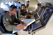 Two members of the Indonesian Navy's Tactical Commanding Operator (TACCO) help with the search for AirAsia flight QZ 8501 on board a CN235 aircraft over Karimun Java, in the Java Sea December 28, 2014. PHOTO BY REUTERS/Eric Ireng