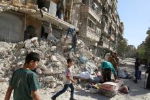 People remove belongings from a damaged site after an air strike Sunday in the rebel-held besieged al-Qaterji neighbourhood of Aleppo, Syria. PHOTO BY REUTERS/Abdalrhman Ismail
