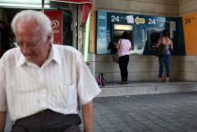 People withdraw money from automated teller machines in Nicosia, Cyprus, June 21, 2015. PHOTO BY REUTERS/Yiannis Kourtoglou
