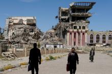 People walk in front of the remains of the University of Mosul, which was burned and destroyed during a battle with Islamic State militants, in Mosul, Iraq, April 10, 2017. PHOTO BY REUTERS/Marko Djurica