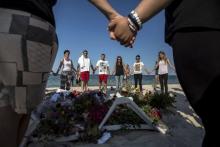 People hold hands as they pray in a circle around bouquets of flowers laid as mementos on the beach of the Imperial Marhaba resort, which was attacked by a gunman, in Sousse, Tunisia, June 28, 2015. PHOTO BY REUTERS/Zohra Bensemra
