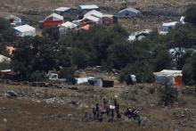 People wave white cloths next to the refugee tents erected near the border fence between Israel and Syria from its Syrian side as it is seen from the Israeli-occupied Golan Heights near the Israeli Syrian border, July 17, 2018. PHOTO BY REUTERS/Ronen Zvulun