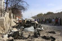 People look at the scene of a suicide attack next to the gate of the Presidential Palace in Mogadishu
