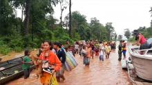 People walk through flooded area after being brought to safety by boat in Sanam Xay district, Attapeu Province, Laos after a hydropower dam under construction in Southern Laos collapsed, in this still picture taken from social media video obtained, July 24, 2018. PHOTO BY REUTERS/ATTAPEU TODAY