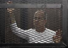 Al Jazeera journalist Peter Greste of Australia stands in a metal cage during his trial in a court in Cairo, March 24, 2014. PHOTO BY REUTERS/Al Youm Al Saabi Newspaper
