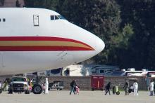 Women and children walks past personnel in protective clothing after arriving on an aircraft, chartered by the U.S. State Department to evacuate government employees and other Americans from the novel coronavirus threat in the Chinese city of Wuhan, at March Air Reserve Base in Riverside County, California, U.S., January 29, 2020. PHOTO BY REUTERS/Mike Blake