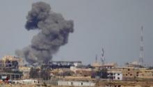 A plume of smoke rises above a building during an air strike in Tikrit, March 27, 2015. PHOTO BY REUTERS/Thaier Al-Sudani