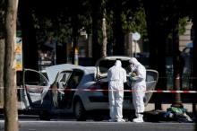 Members of the scientific police inspect a burned car at the scene of an incident in which a car rammed a gendarmerie van on the Champs-Elysees Avenue in Paris, France, June 19, 2017. PHOTO BY REUTERS/Gonzalo Fuentes