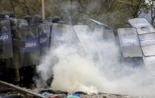 Macedonian police officers try to take cover from tear gas thrown back by a stranded migrant, as minor clashes broke out during a protest against the building of a metal fence at the Greek-Macedonian borders near the village of Idomeni, Greece, November 28, 2015. PHOTO BY REUTERS/Yannis Behrakis