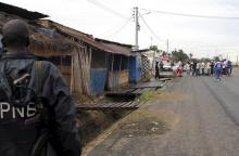 A policeman watches from a distance as residents gather near the bodies of unidentified men killed during gunfire, in the Nyakabiga neighbourhood of Burundi's capital Bujumbura, December 12, 2015. PHOTO BY  REUTERS/Jean Pierre Aime 