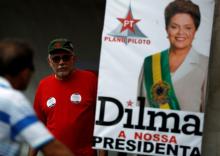 People walk next to an official photo of Brazil's suspended President Dilma Rousseff, at a camp in support of Rousseff, in Brasilia, Brazil, August 28, 2016. PHOTO BY REUTERS/Bruno Kelly