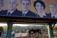 A man walks with a horse near a campaign poster for the National Democratic Assembly party in the Israeli-Arab city of Umm el-Fahm, January 14, 2013. PHOTO BY REUTERS/Ammar Awad