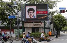 People ride their motorcycles past a digital billboard showing a sketch of the main suspect in Monday's attack on Erawan shrine, in Bangkok, Thailand, August 23, 2015. PHOTO BY REUTERS/Chaiwat Subprasom
