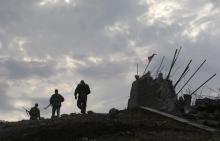 Pro-Russian separatists walk at a destroyed war memorial on Savur-Mohyla, a hill east of the city of Donetsk