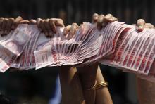 Anti-government protesters hold Thai baht banknotes to donate to protest leader Suthep Thaugsuban (unseen) as he leads a march through central Bangkok