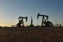 Pump jacks operate in front of a drilling rig in an oil field in Midland, Texas U.S., August 22, 2018. PHOTO BY REUTERS/Nick Oxford