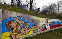 Graffiti depicting Russian President Vladimir Putin (R) extending a hand to the Ukrainian people is seen on a wall in the Crimean city of Simferopol