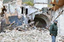 An officer of the State Forestry Corp national police stands in front of a collapsed church in Campi di Norcia, central Italy, October 27, 2016. PHOTO BY REUTERS/Emiliano Grillotti