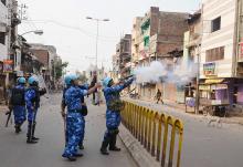 A Rapid Action Force (RAF) member fires a tear gas shell to disperse a mob after clashes in Vadodara in the western Indian state of Gujarat