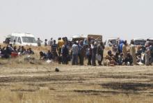 Syrian refugees wait near the border fences as they are pictured from the Turkish side of the border, near Akcakale in Sanliurfa province, Turkey, June 11, 2015. PHOTO BY REUTERS/Osman Orsal