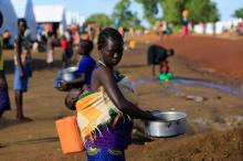 A South Sudanese refugee woman cleans a pot, while carrying a child, at the Palabek Refugee Settlement Camp in Lamwo district, Uganda, June 16, 2017. PHOTO BY REUTERS/James Akena