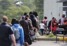 A group of asylum seekers wait to be processed after being escorted from their tent encampment to the Canada Border Services in Lacolle, Quebec, Canada, August 11, 2017. PHOTO BY REUTERS/Christinne Muschi